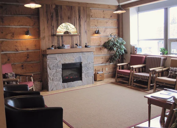 The patient lounge at the practice, with a stone fireplace and timber walls